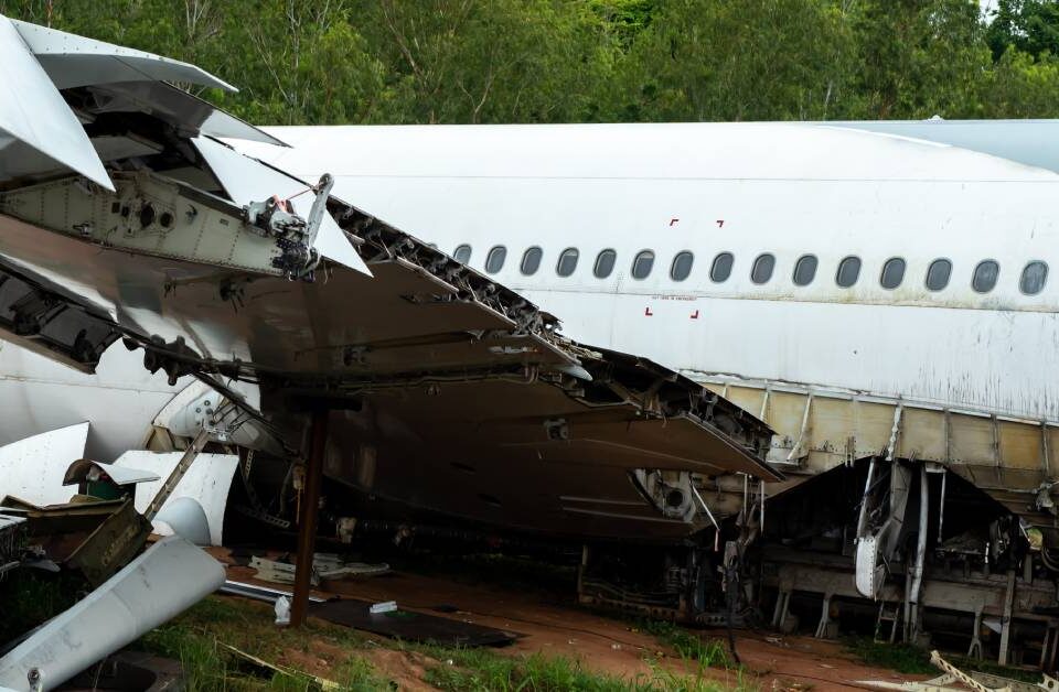 A large passenger airplane that has crashed to the ground. One wing has crumpled, and there are no people visible.