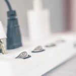 A power strip with three cables plugged into it. The plug in the foreground is noticeably damaged and burnt.