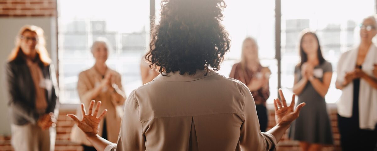 The backside of a businesswoman empowering other colleagues in the workplace during a quick team meeting.