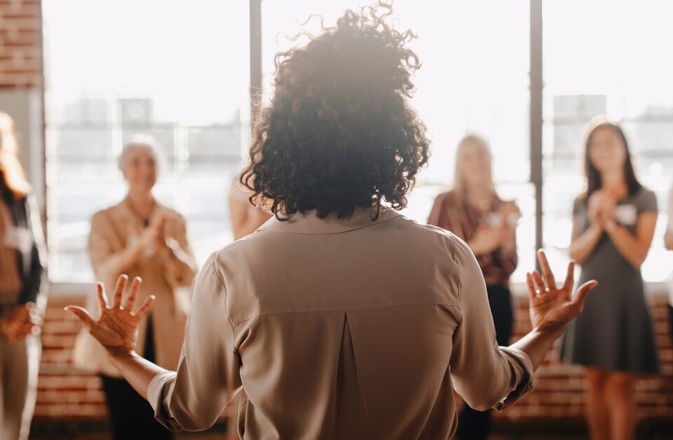The backside of a businesswoman empowering other colleagues in the workplace during a quick team meeting.