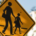 A yellow pedestrian crossing sign that features an adult and child walking across a road.