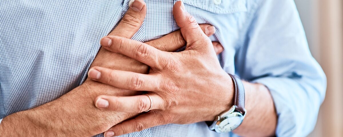 A man experiencing chest discomfort is pressing both of his hands over his heart.