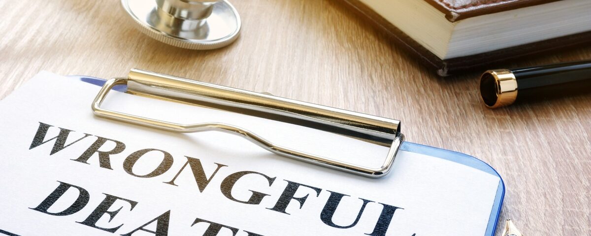 A close-up of a clipboard with a piece of paper displaying the words “wrongful death” next to a stethoscope and a book.