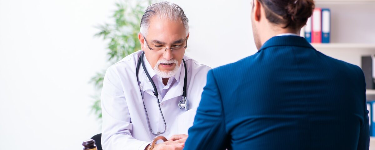 A man wearing a blue suit, sitting across from a man wearing a white robe behind a desk with a wooden gavel on top.